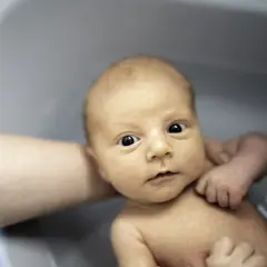 Niemowlę w wanience, z zaciekawieniem patrzy na świat. Czy można kąpać dziecko po szczepieniu? Tak, jeśli nie ma przeciwwskazań lekarza.
