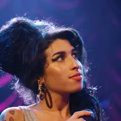 Amy Winehouse, z charakterystyczną fryzurą i makijażem, śpiewa smutne piosenki o mamie.