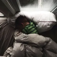 Chłopiec śpi pod kołdrą, przytulony do poduszki. Czy to początek lunatykowania?