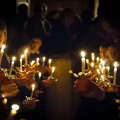 Dzieci trzymają zapalone świece, tworząc magiczną atmosferę. To piękny obraz zmartwychwstania dla dzieci.