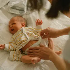 Mama zmienia pieluchę noworodkowi. Jakie pieluchy dla noworodka wybrać, by maluszkowi było wygodnie?