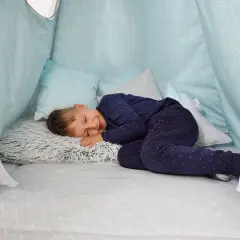 Chłopiec śpi w domowej bazie z poduszkami. Idealne miejsce, by odpocząć po zabawie.