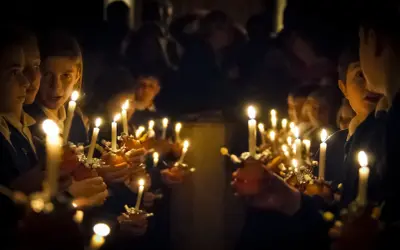 Dzieci trzymają zapalone świece, tworząc magiczną atmosferę. To piękny obraz zmartwychwstania dla dzieci.