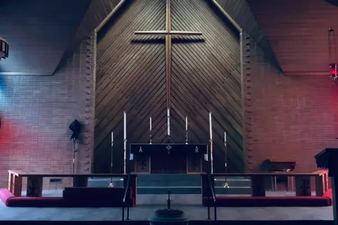 Wnętrze kościoła z ołtarzem, krzyżem i witrażami.