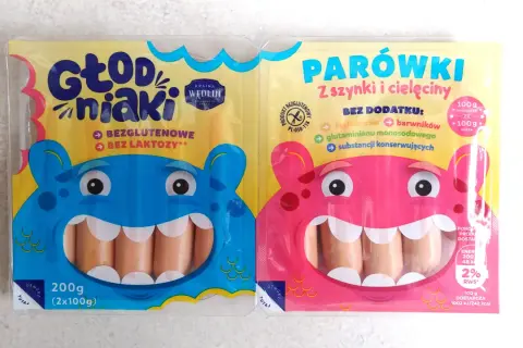 Dwie paczki parówek dla dzieci: niebieska "Głodniaki" bezglutenowe i bez laktozy, różowa "Parówki z szynki i cielęciny" bez dodatków.