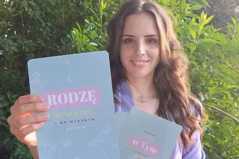 Kobieta trzyma książki z napisem "Rodzę spokojnie" i "Wszystko mogę w tym".