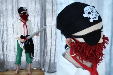 Dziecko w stroju pirata: czarna bandama z czaszką, opaska na oko, czerwona broda z włóczki, biała koszula, zielone spodnie i miecz. Oto jak przebrać dziecko za pirata!