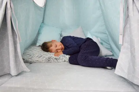 Chłopiec śpi w domowej bazie z poduszkami. Idealne miejsce, by odpocząć po zabawie.