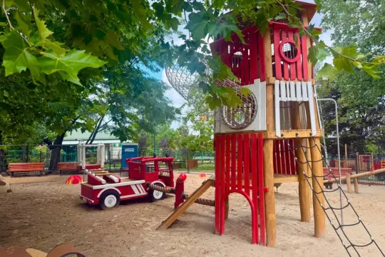 Kolorowy plac zabaw z remizą strażacką i wieżą. Idealne miejsce do zabawy, które zainspiruje do napisania podania o plac zabaw.