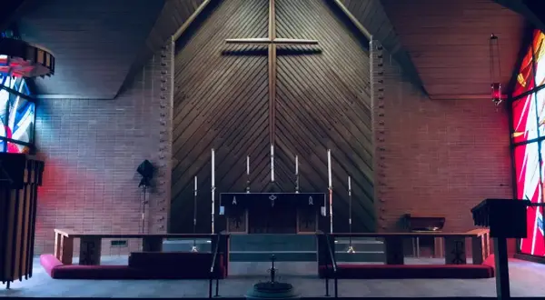 Wnętrze kościoła z ołtarzem, krzyżem i witrażami.