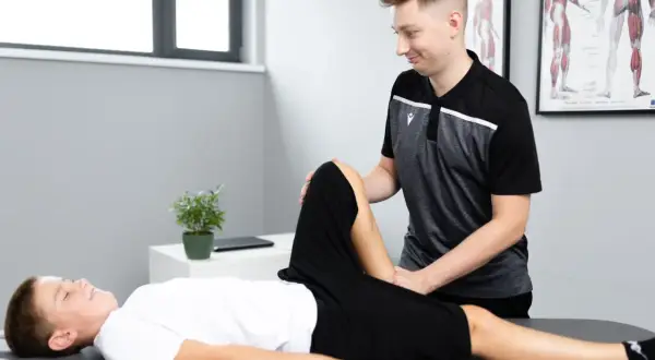 Fizjoterapeuta bada nogę chłopca, który kuleje, ale noga nie boli.