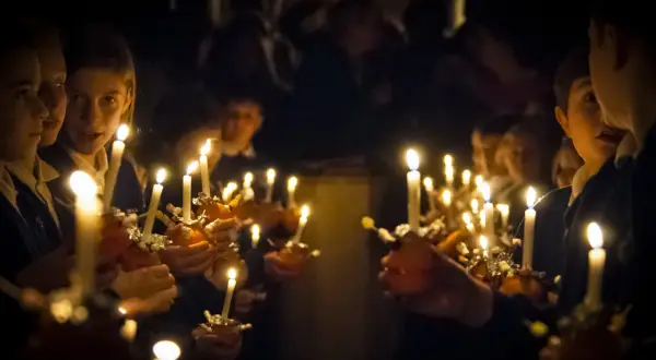 Dzieci trzymają zapalone świece, tworząc magiczną atmosferę. To piękny obraz zmartwychwstania dla dzieci.