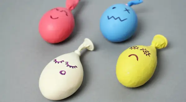 Kolorowe balony z narysowanymi buźkami, gotowe do zabawy. Tak się robi gniotka!