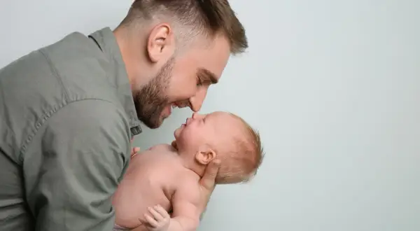 Ojciec pochyla się nad dzieckiem, dotykając noskami. Czy po kim dziecko dziedziczy inteligencję?