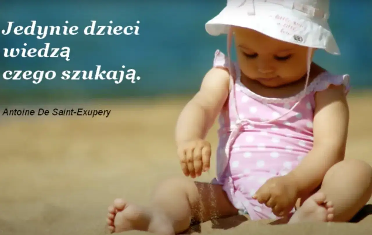 Dziecko na plaży, w różowym stroju w kropki, bawi się piaskiem. Cytat: 