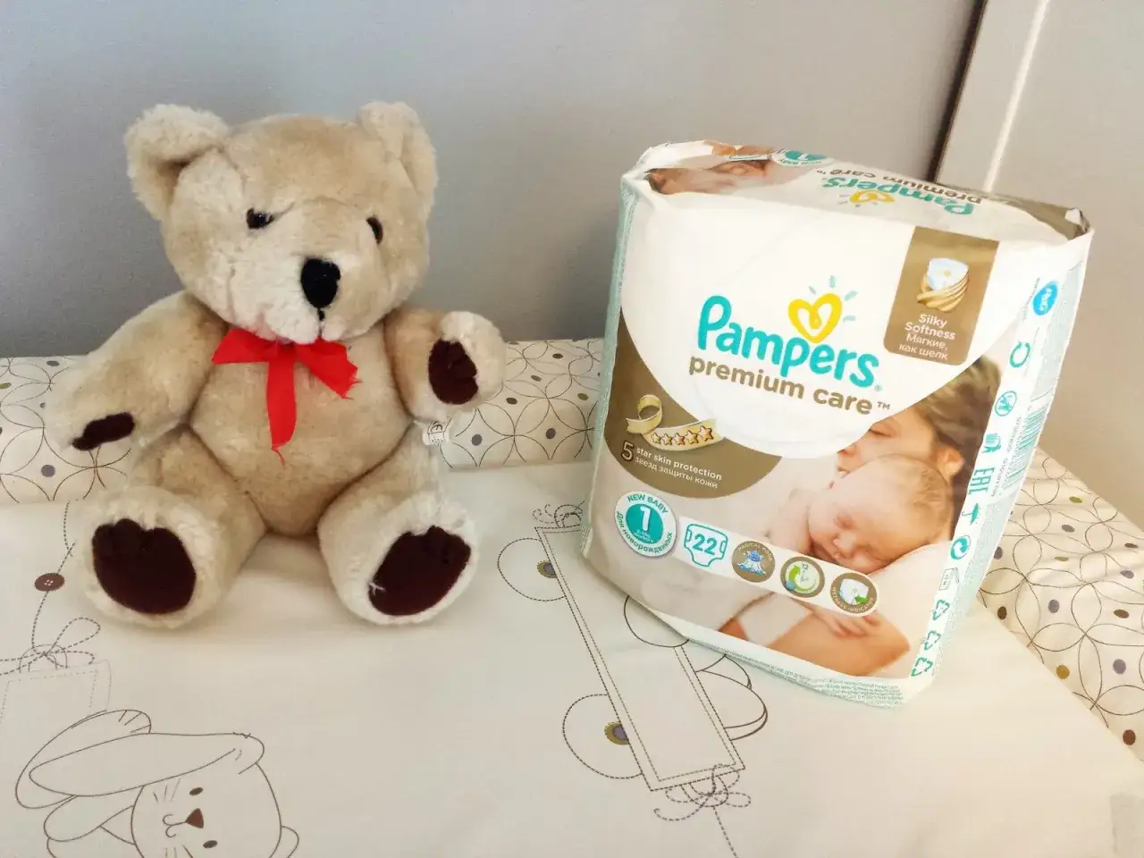 Pluszowy miś i opakowanie pieluch Pampers Premium Care. Idealne pieluchy dla noworodka, zapewniające 5-gwiazdkową ochronę skóry.