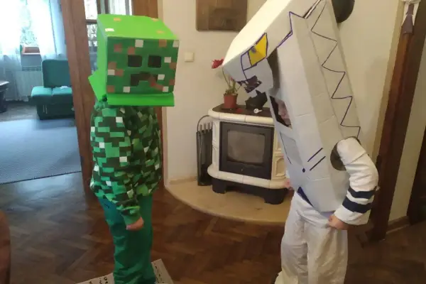Dzieci w strojach z kartonu: jeden w zielonym kostiumie Creepera z Minecrafta, drugi w białym stroju robota. Świetny przykład, jak zrobić strój z kartonu!